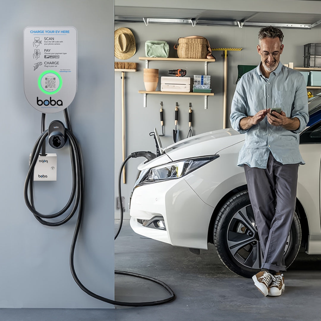 Boba charger mounted in a garage with the green ready light on, EV plugged in and the owner checking his phone