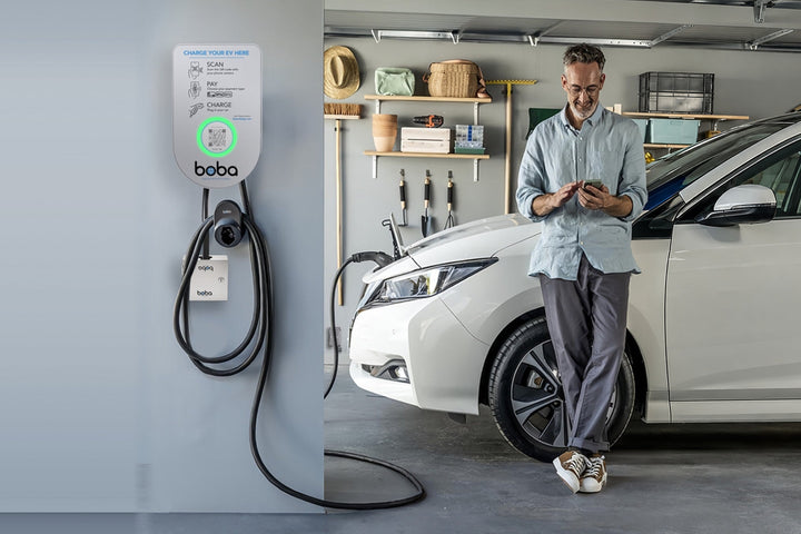 Guest checking the Boba EV charger app next to a wall-mounted Boba charger in a home garage